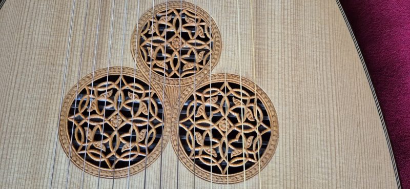Close-up of the triple carved rosettes on Jaume Bosser concert theorbo, showing intricate geometric patterns on spruce soundboard