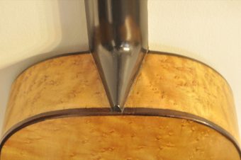 Neck heel joint of Thibouville-Lamy guitar showing black lacquered lime wood neck meeting curly maple body