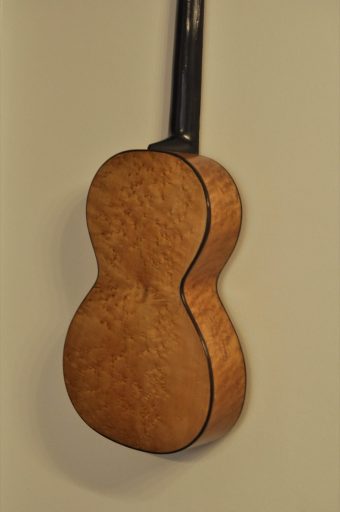 Back three-quarter view of Thibouville-Lamy romantic guitar displaying birdseye maple back and sides