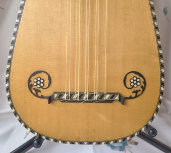 Decorative bridge of a Stephen Barber baroque guitar with carved mustache scrolls and mother-of-pearl flower inlays