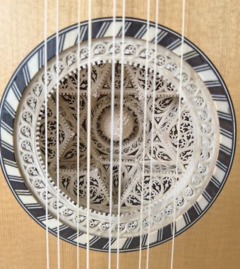 Detail of the multi-layered carved parchment rosette of a Stephen Barber baroque guitar with intricate geometric patterns