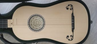 Spruce soundboard of a Karl Kirchmeyr baroque guitar with a multi-layered parchment rosette and an ornate carved bridge