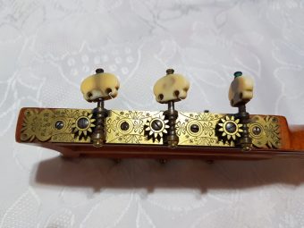 Detail of the engraved brass Baker tuning machines on a Louis Panormo guitar, stamped BAKER, with ivory peg heads