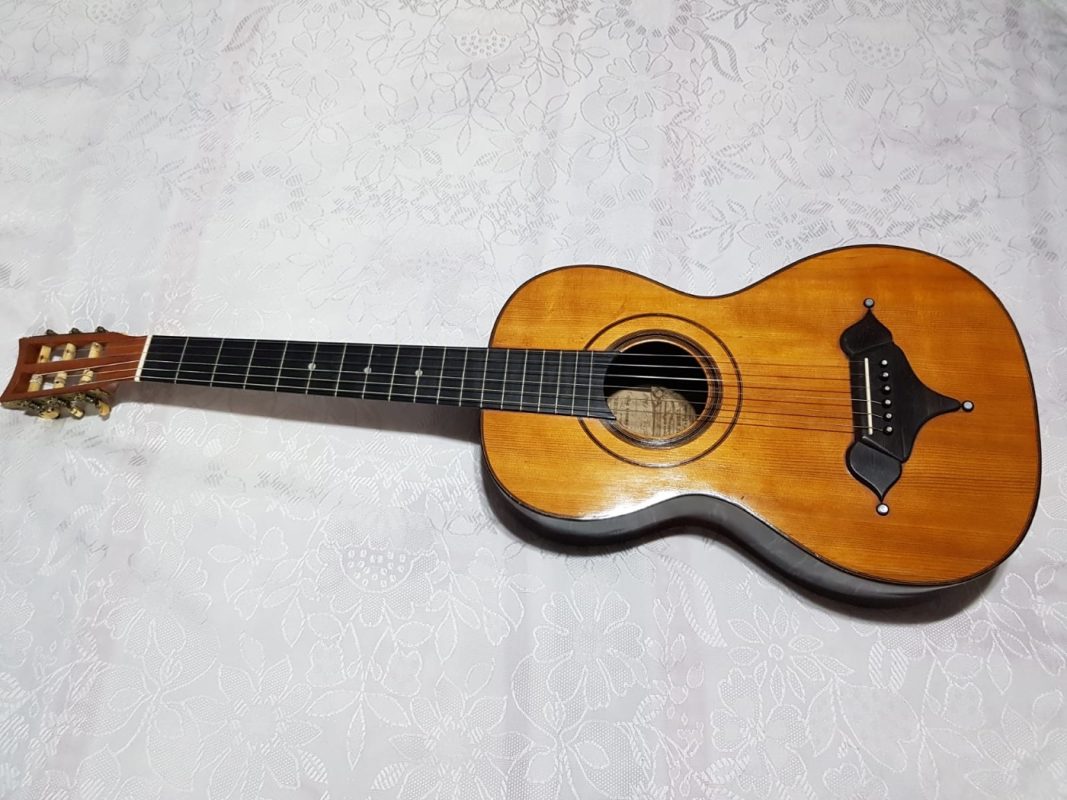 Front view of an 1849 Louis Panormo romantic guitar with spruce top, ebony moustache bridge and slotted headstock