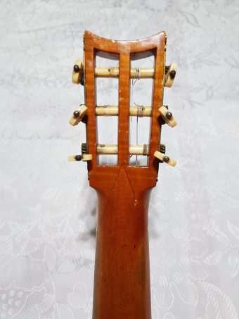 Reverse of the slotted headstock of a Louis Panormo guitar showing the ivory tuner buttons and the neck V-joint