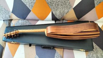 Angled view of the back and side of the César Arias baroque guitar showing the fluted body and the neck