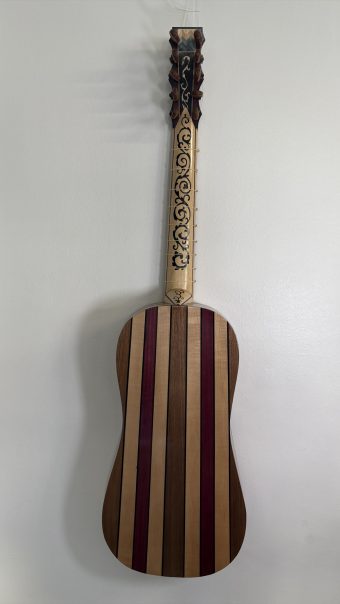 Back of the Régis Floury baroque guitar built from alternating strips of maple, walnut and purpleheart separated by dark fillets, with an inlaid neck