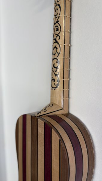 Profile of the Régis Floury baroque guitar showing the marquetry neck with black scrollwork, the tied frets and the striped ribs of the body