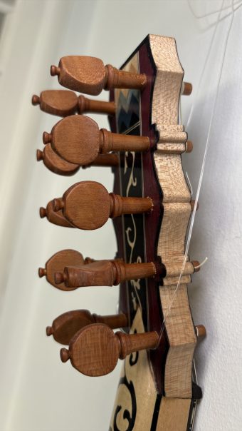 Side view of the turned wooden pegs of the Régis Floury baroque guitar, showing the flat heads and the profile of the inlaid pegbox