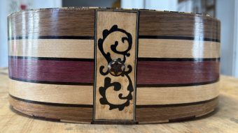 Bottom rib of the Régis Floury baroque guitar with a marquetry panel of black scrollwork around the end pin, between the striped maple and walnut ribs