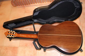 Two-piece rosewood back of the Paco Santiago Marín classical guitar with a light centre strip, beside its open Bam case