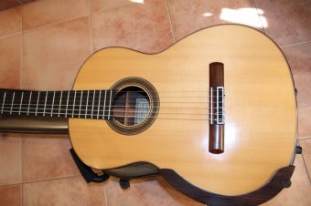 Spruce soundboard of the 2004 Paco Santiago Marín classical guitar, with its rosette, wooden armrest and rosewood binding