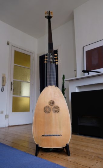 Full front view of a 14-course theorbo by Jaume Bosser (1987) on a stand, showing the three carved rosettes, ebony fingerboard and double pegbox