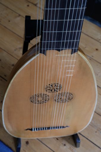 Close-up of the soundboard of the Jaume Bosser theorbo with three finely carved rosettes in a trefoil and the bridge with strings tied on