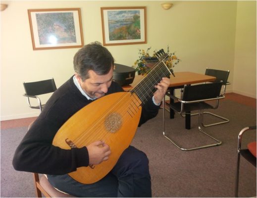 The Hans Jordan 13-course baroque lute held in playing position, showing its scale and the reach of the bass rider