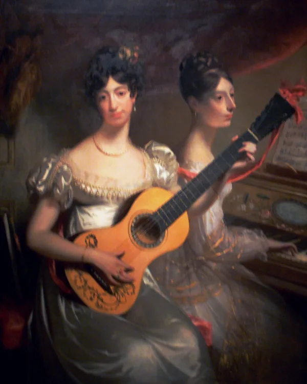 Dos jóvenes con vestidos blancos; una de ellas toca la guitarra